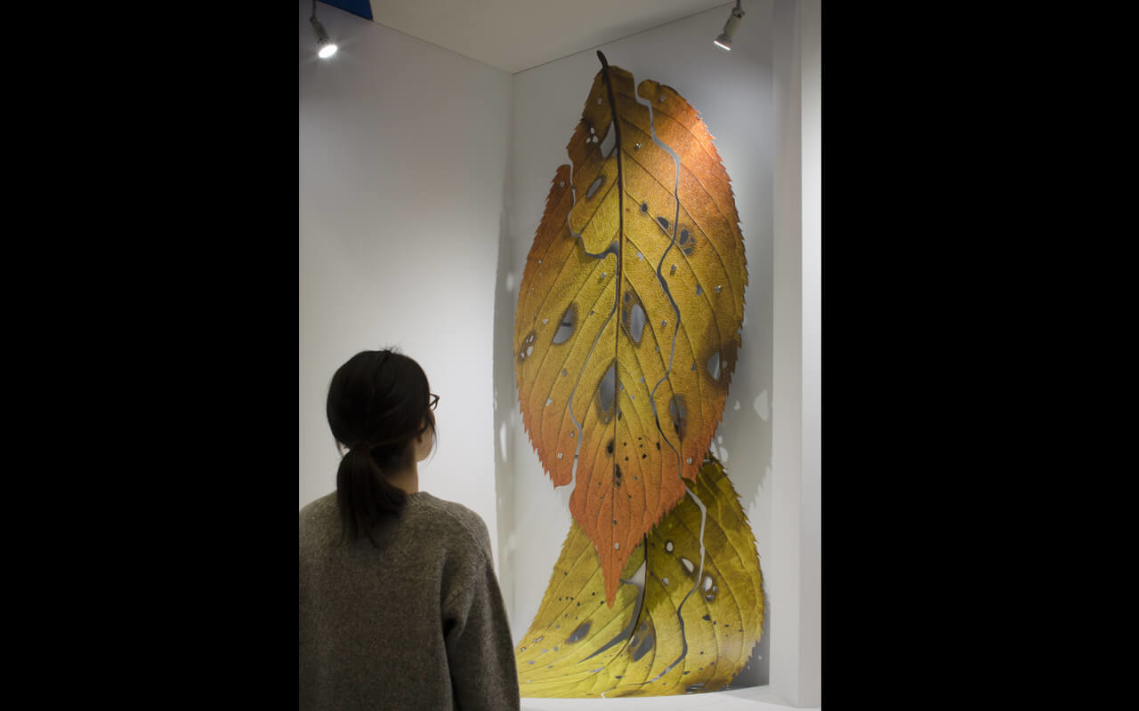 「4features」と名付けられたこの巨大な葉は日鉄日新製鋼株式会社様の開発品である「高意匠イクジェット印刷鋼板」を用いたオブジェであり、 インクジェット印刷鋼板の4つの技術的特徴を活かすことで造られています。